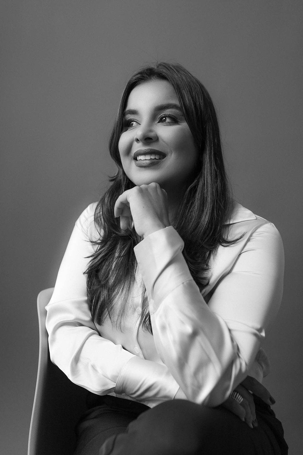 Rafaela Fidelis sentada em pose reflexiva, com a mão no rosto, transmitindo acolhimento e profissionalismo como psicóloga.